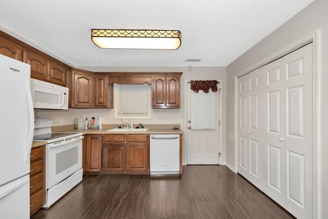 kitchen with brown cabinets, white appliances, light countertops, and a sink