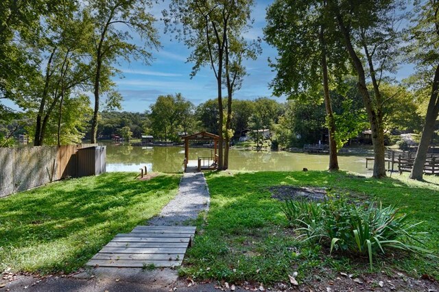 view of property's community with a yard, a dock, and a water view