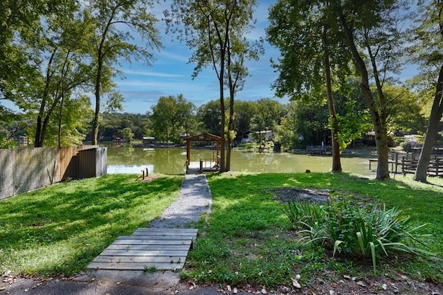 view of property's community featuring a yard, a water view, and fence