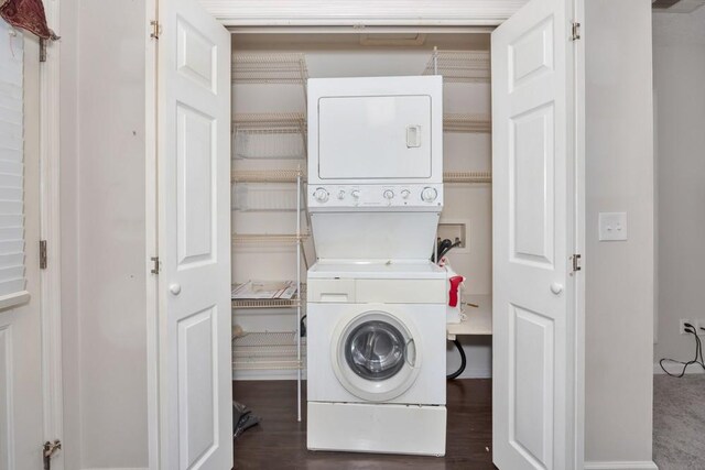 laundry area featuring dark wood-type flooring and stacked washer / dryer