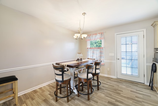 dining area with light wood-type flooring, a wealth of natural light, and a chandelier