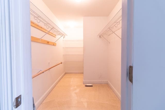 walk in closet featuring light colored carpet