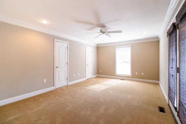 carpeted empty room with ceiling fan and crown molding