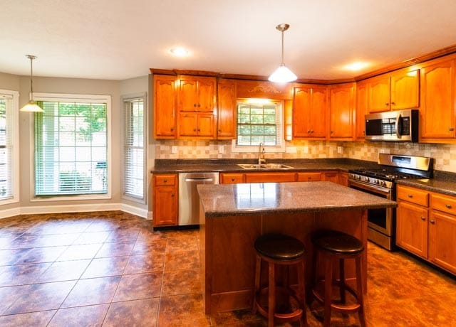 kitchen featuring sink, stainless steel appliances, pendant lighting, a kitchen island, and dark tile patterned flooring