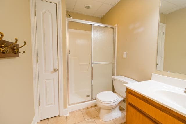 bathroom with a paneled ceiling, vanity, walk in shower, and tile patterned floors