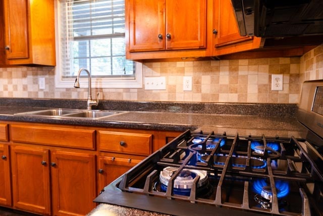 kitchen with tasteful backsplash, stainless steel gas stovetop, and sink