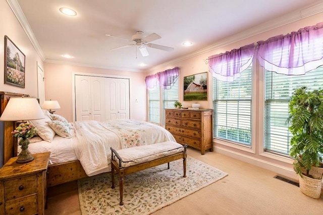 carpeted bedroom with ceiling fan, ornamental molding, and a closet