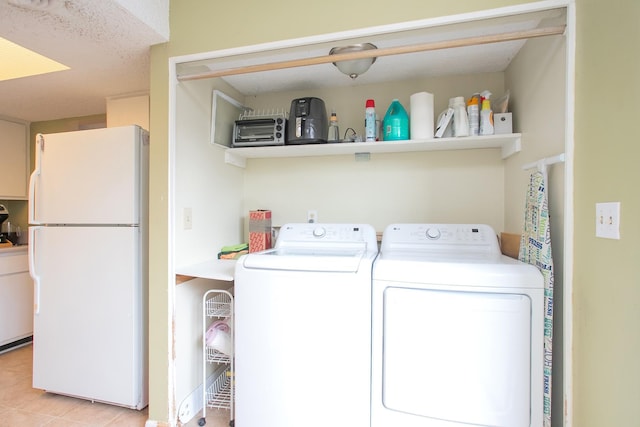 laundry area with independent washer and dryer and light tile patterned floors