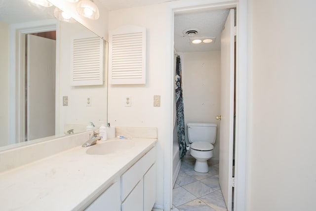 bathroom with tile patterned flooring, a textured ceiling, vanity, and toilet