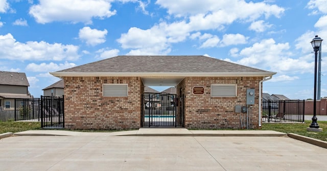 exterior space with a shingled roof, a gate, brick siding, and fence