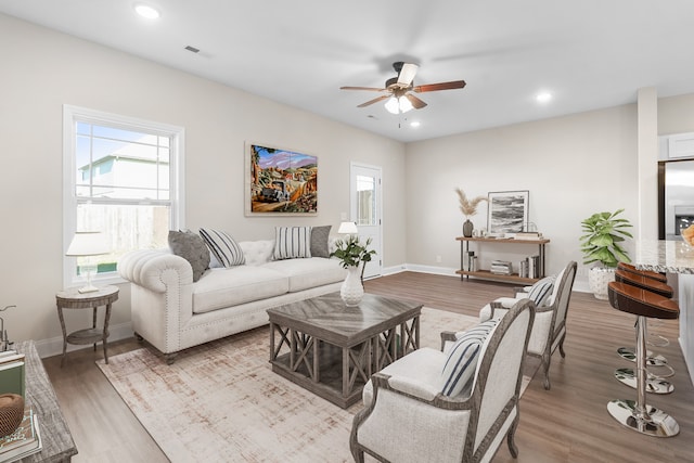 living room featuring baseboards, ceiling fan, light wood-type flooring, and recessed lighting