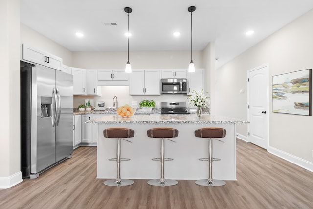 kitchen featuring light wood-type flooring, white cabinetry, light stone countertops, and stainless steel appliances