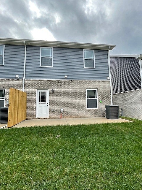 rear view of house featuring a yard, brick siding, central AC, and a patio area