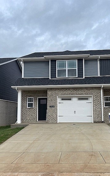 view of front of house featuring concrete driveway, brick siding, roof with shingles, and an attached garage