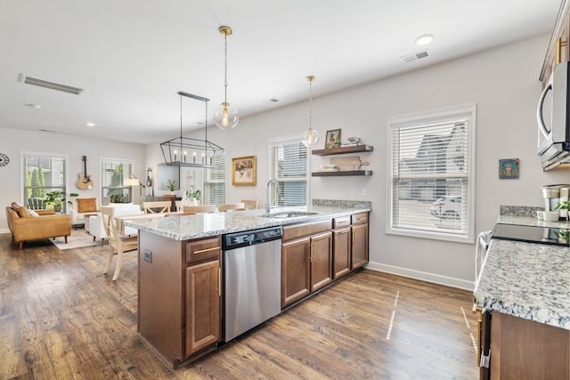 kitchen with appliances with stainless steel finishes, decorative light fixtures, sink, and light stone countertops