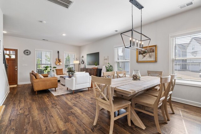 dining area featuring dark wood-type flooring and an inviting chandelier