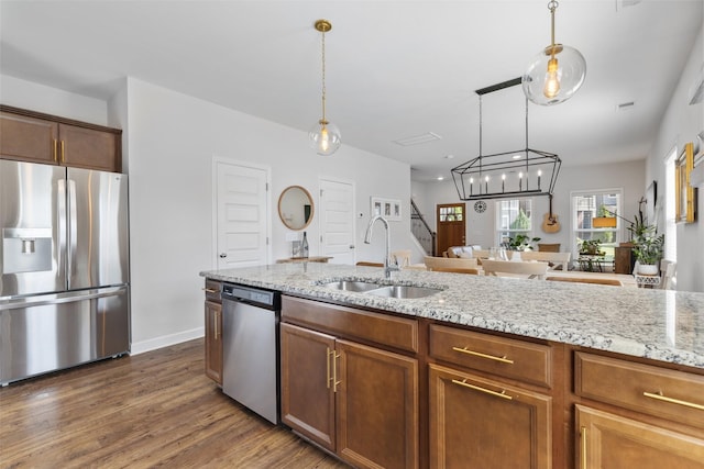 kitchen with appliances with stainless steel finishes, sink, pendant lighting, and dark hardwood / wood-style floors