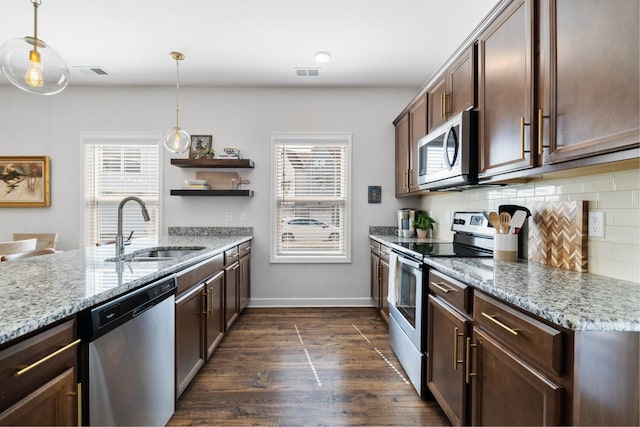 kitchen featuring hanging light fixtures, stainless steel appliances, light stone counters, and sink