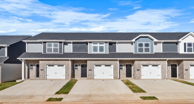 multi unit property featuring driveway, brick siding, an attached garage, and roof with shingles