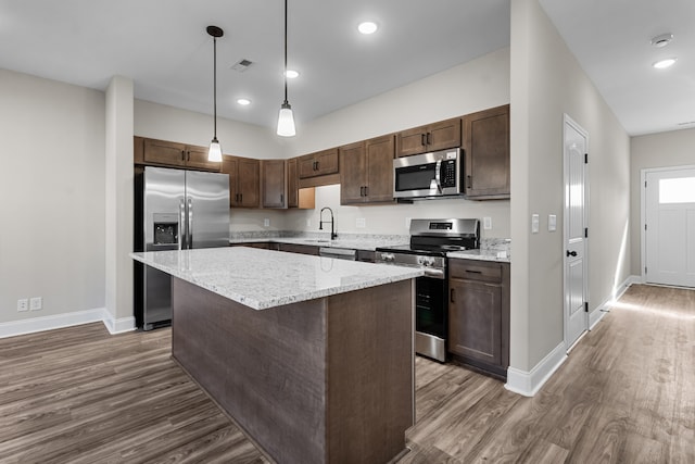 kitchen with dark wood-style floors, stainless steel appliances, visible vents, a kitchen island, and dark brown cabinetry