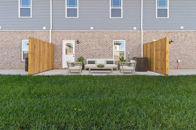 back of property featuring a patio area, brick siding, an outdoor living space, and a lawn