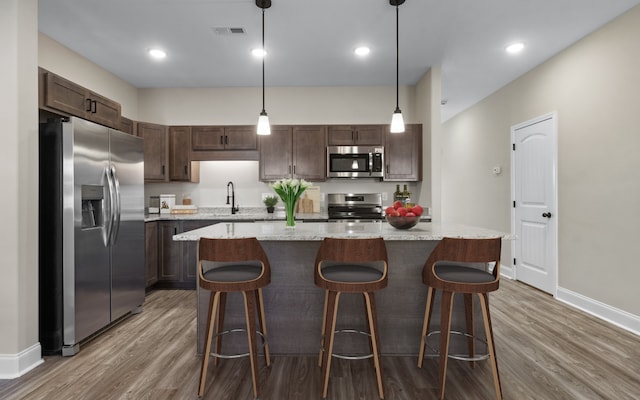 kitchen featuring dark brown cabinetry, a sink, wood finished floors, visible vents, and appliances with stainless steel finishes