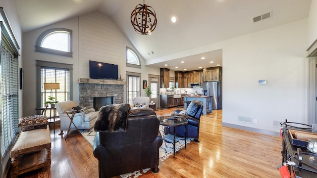 living room featuring a fireplace, high vaulted ceiling, and light hardwood / wood-style floors