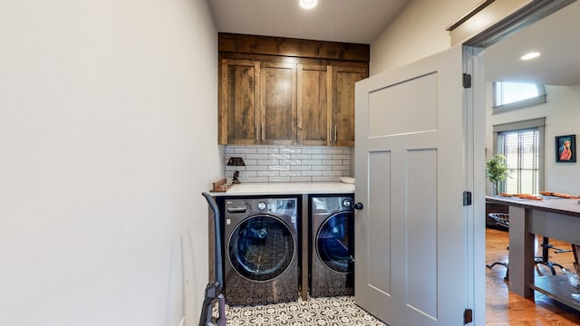 clothes washing area featuring light tile patterned flooring, washer and clothes dryer, and cabinets