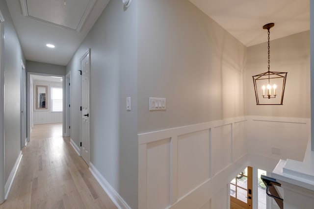 hallway featuring light wood-type flooring, plenty of natural light, and a notable chandelier