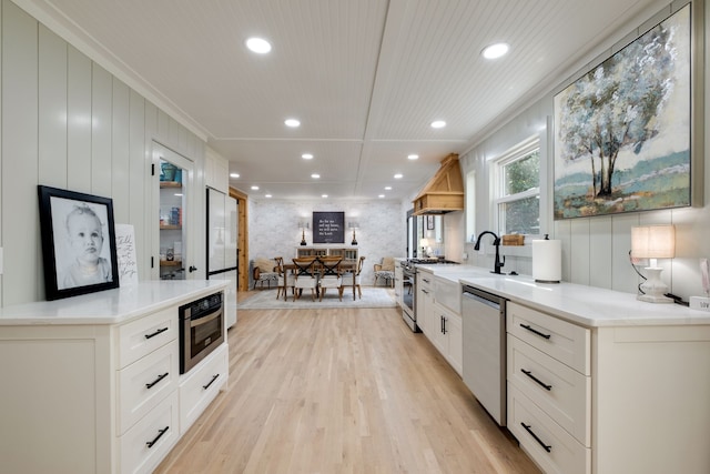 kitchen featuring appliances with stainless steel finishes, crown molding, white cabinetry, and light wood-type flooring