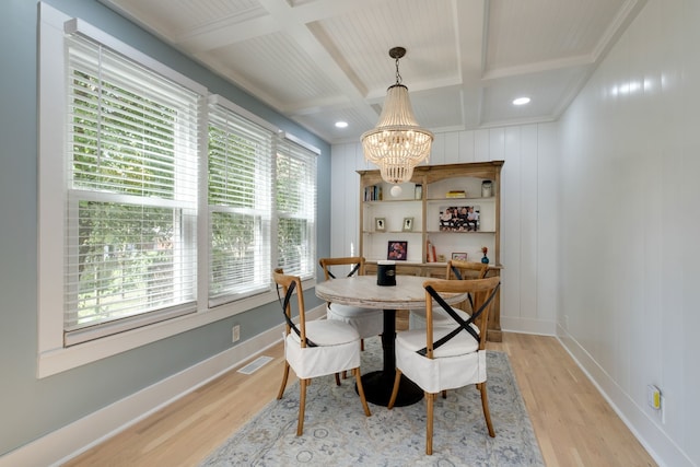 dining room with a wealth of natural light, a notable chandelier, light wood-type flooring, and coffered ceiling