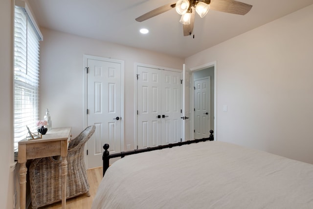 bedroom featuring ceiling fan, light wood-type flooring, and two closets