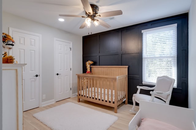 bedroom with light hardwood / wood-style floors, a nursery area, and multiple windows