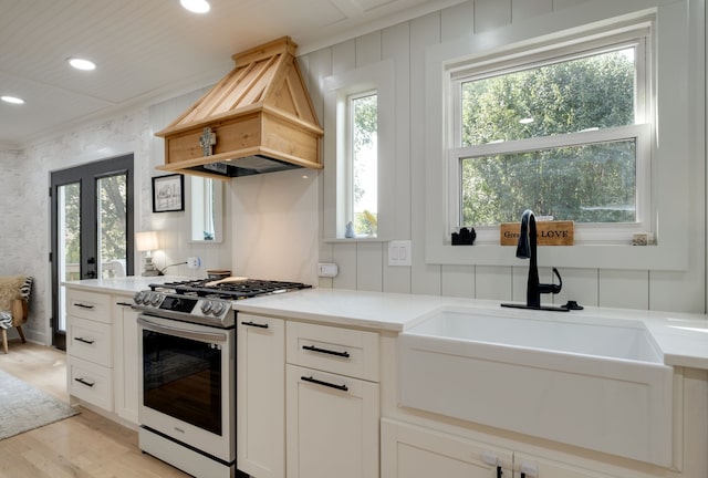 kitchen featuring stainless steel range with gas stovetop, light hardwood / wood-style floors, a healthy amount of sunlight, and custom range hood