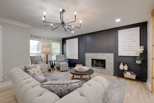 living room featuring a fireplace, light hardwood / wood-style flooring, crown molding, and an inviting chandelier