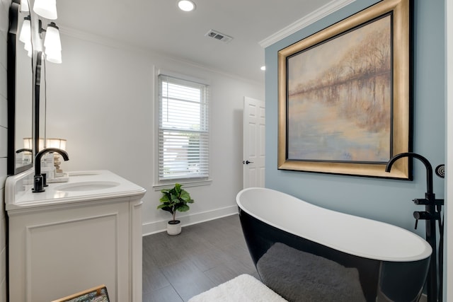 bathroom featuring hardwood / wood-style flooring, crown molding, vanity, and a bathtub