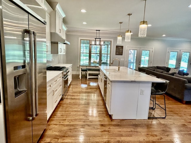 kitchen featuring sink, light wood-type flooring, french doors, white cabinetry, and premium appliances