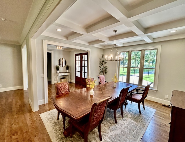 dining room featuring light wood-type flooring, coffered ceiling, french doors, a notable chandelier, and beamed ceiling