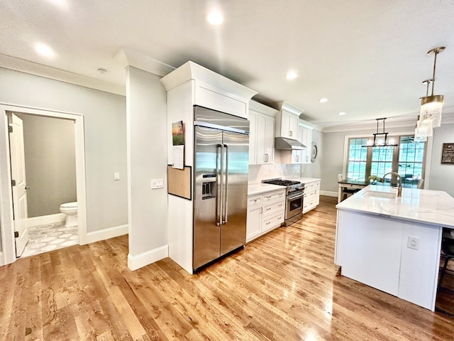 kitchen featuring high end appliances, decorative light fixtures, light hardwood / wood-style floors, and white cabinets