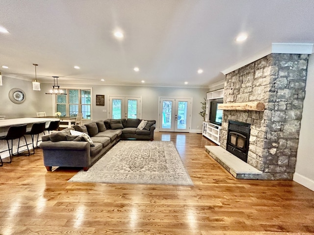 living room featuring a fireplace, light hardwood / wood-style flooring, crown molding, and french doors