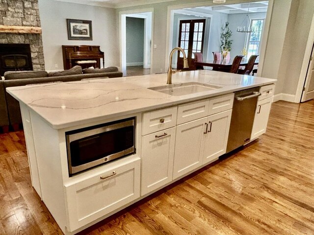 kitchen with light hardwood / wood-style flooring, white cabinets, sink, a fireplace, and stainless steel appliances