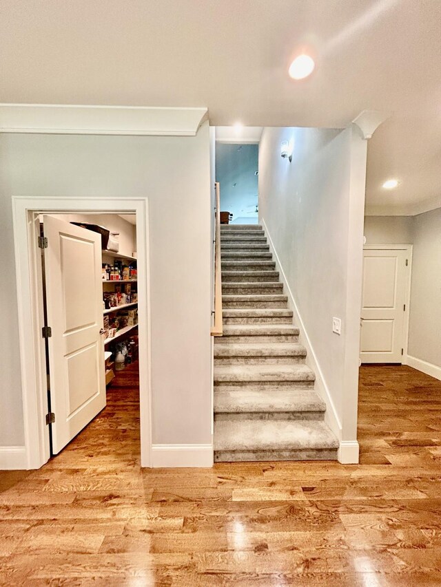 staircase featuring crown molding and wood-type flooring