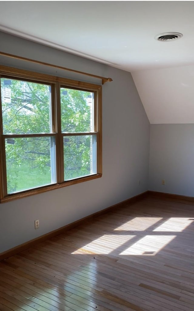 bonus room featuring vaulted ceiling, baseboards, visible vents, and wood-type flooring