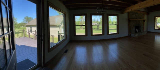 unfurnished sunroom with beamed ceiling and a fireplace