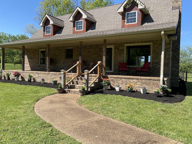 view of front of home featuring brick siding, covered porch, a front lawn, and a shingled roof