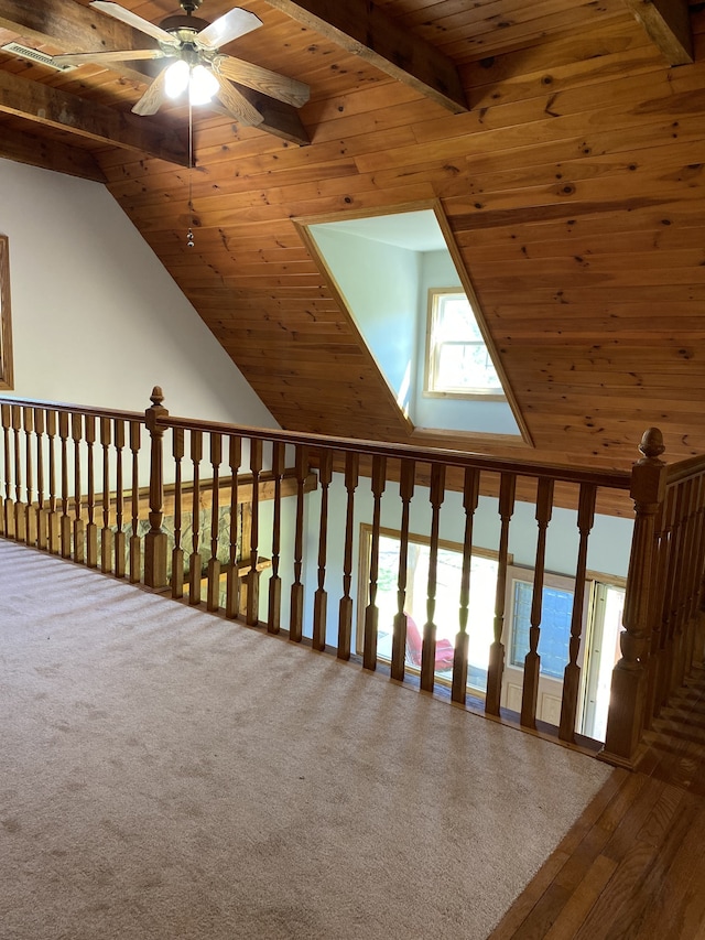 interior space featuring carpet floors, ceiling fan, wooden ceiling, and vaulted ceiling with beams