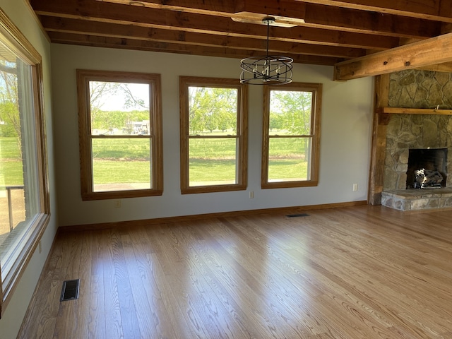 unfurnished living room with a fireplace, beam ceiling, and hardwood / wood-style floors