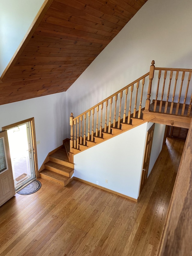 staircase featuring vaulted ceiling, wooden ceiling, baseboards, and wood finished floors