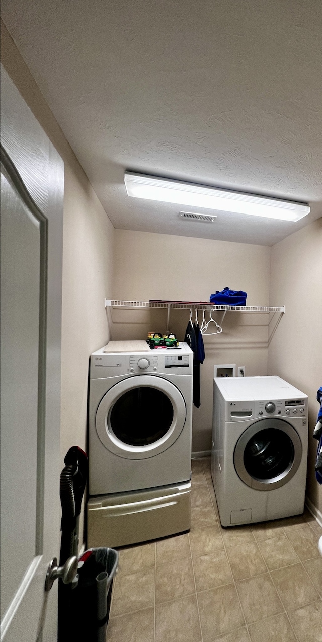 laundry room with light tile patterned flooring and washer and clothes dryer