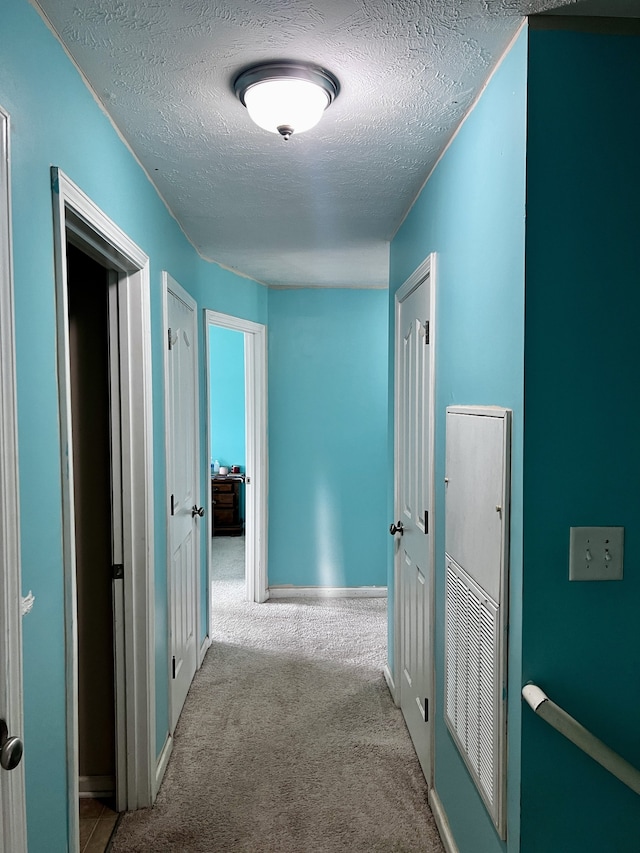 corridor featuring carpet and a textured ceiling